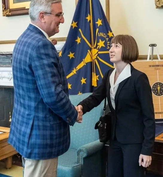 A photo of a student and faculty member shaking hands