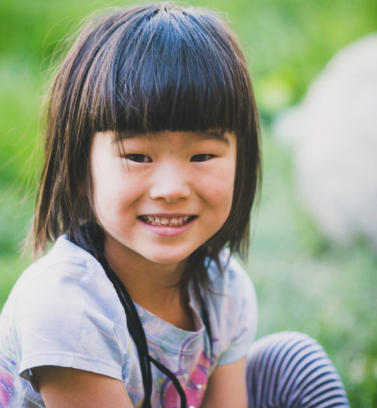 A young girl outdoors smiling at the camera