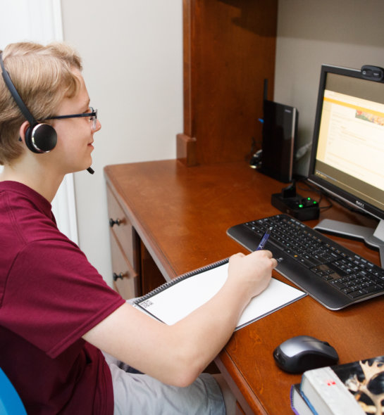 A boy with a headset sitting at the computer