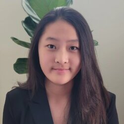 Teenage girl in a blazer smiling in front of a plant