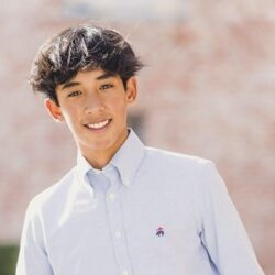 Teenage boy smiling in front of a brick background