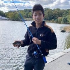 Boy smiling with fishing pole in hand on a dock in a lake